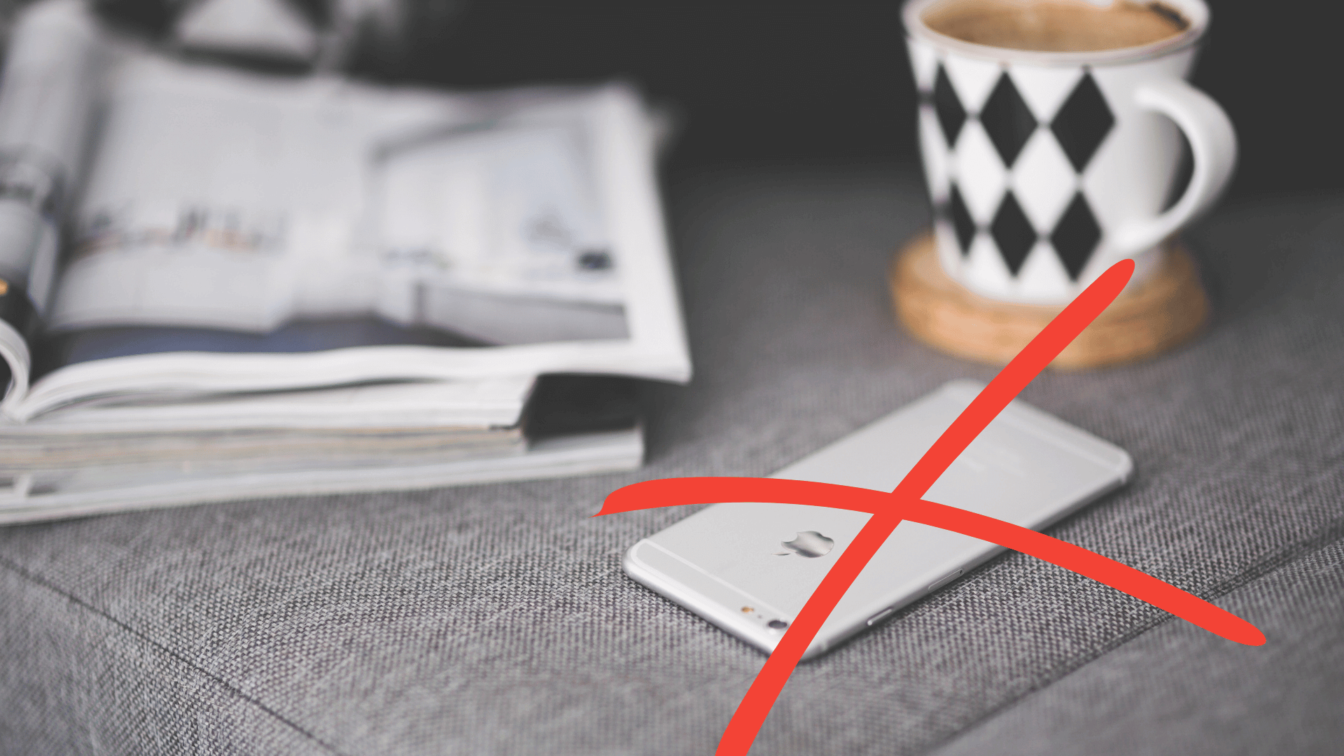 przekreślony telefon obok kubka i książek